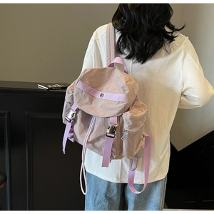Detail view of light purple nylon backpack featuring silver metal buckles and waterproof fabric