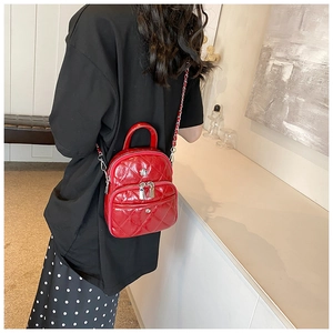 Détail du mini sac matelassé rouge avec bandoulière chaîne en argent porté par un modèle