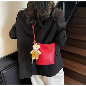 Macro detail of red lychee pattern bucket bag with a cute bear charm on model's back