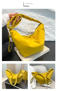 Detail of yellow nylon dumpling bag featuring a wide scrunched shoulder strap design