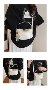 Detail view of cream oil wax leather crossbody bag with pearl chain and doll charm