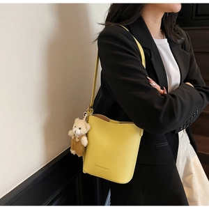Detail of yellow lychee leather bucket bag with a cute bear charm and fashion text