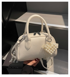 Dettaglio mini borsa bowling bianca con ciondolo a cuore di perle e tracolla