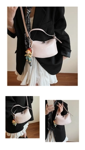 Detail view of pink oil wax leather crossbody bag with doll pendant and pearl chain