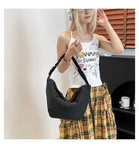 Detail of the black hobo bag with a stylish scrunchie-style pleated shoulder strap