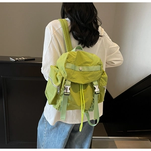 Detail of green nylon backpack showing flap cover with silver metal buckle and drawstring