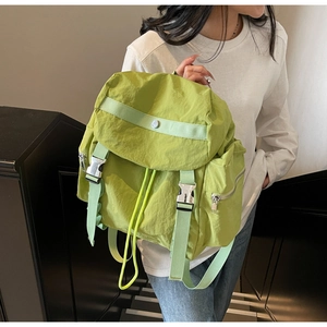Detail of avocado green nylon backpack featuring silver buckles and drawstring closure