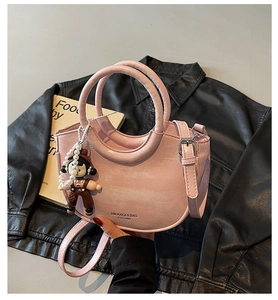 Detail view of pink PU leather crescent bag with pearl chain and cartoon charm decoration