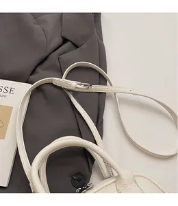 Dettaglio borsa avorio con motivo litchi, tracolla regolabile e cuciture di precisione