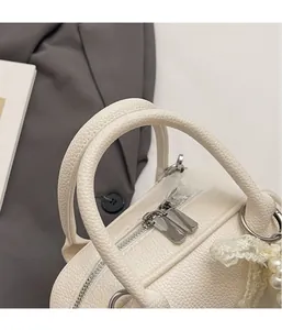 Dettaglio borsa in pelle martellata bianco crema con ciondolo di perle e finiture argento