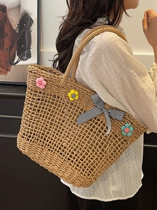 Artistic woven straw basket bag with floral charms and large capacity for beach