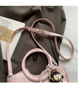 Detailed shot of pink faux leather bucket bag with pearl chain and cartoon charm accessory