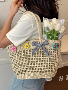 Artistic hand-woven straw tote bag with 3D floral accents and checkered bow for beach