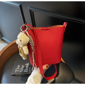 Close-up of red lychee pattern bucket bag featuring magnetic closure and a cute bear charm