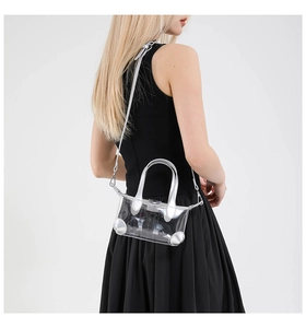 Detailansicht der transparenten PVC-Umhängetasche mit silbernen Griffen an einem Model