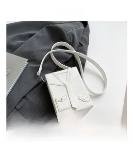 Detail of creative white blazer-shaped box bag with tie decor and pebble leather texture