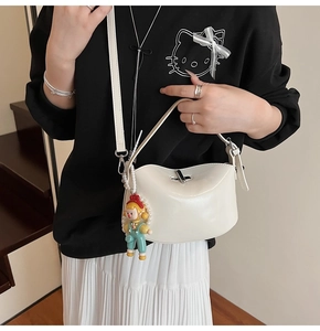 Minimalist creamy white leather crossbody bag with silver lock and a cute doll charm