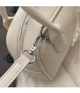 Dettaglio del gancio girevole argento e pizzo bianco sulla borsa in pelle bianco crema