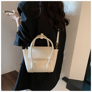 Détail d'un sac seau blanc en similicuir minimaliste avec des finitions dorées chic