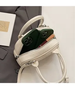 Vista dettagliata dell'interno della borsa in pelle crema con telefono e rossetto