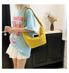 Close-up of a yellow crescent bag featuring a textured pleated shoulder strap and nylon fabric