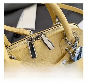 Detail of yellow lychee leather bag featuring double zippers and a heart charm