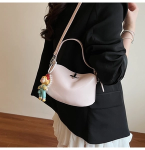 Detail of pink faux leather handbag with pearl chain and cartoon doll charm on shoulder