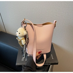 Detailed macro view of pink lychee textured bucket bag with a cute teddy bear charm
