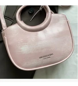 Detail of pink leather bucket bag with rounded handle and pearl-like finish texture