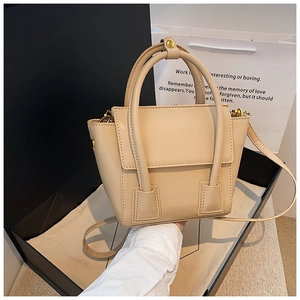 Détail d'un sac seau en cuir crème avec poignée supérieure et ferrures dorées sur boîtes