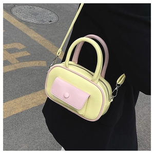 Detailansicht der Mini-Boston-Tasche aus hellgelbem Leder mit rosafarbenen Akzenten am Griff