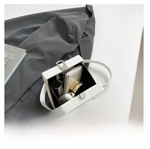 Interior view of white pebble leather box bag showing capacity for phone and makeup