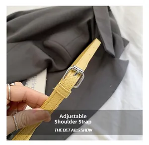 Close-up of yellow lychee leather adjustable shoulder strap with silver metal buckle