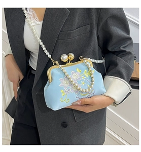 Detail of light blue embroidered evening bag with pearl strap and vintage frame
