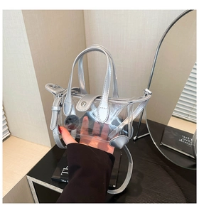 Detail einer silbernen transparenten PVC-Handtasche mit runden Ausschnitten und Leder