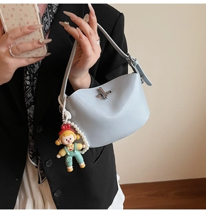 Close-up of light blue oil wax leather handbag with silver lock and pearl doll charm