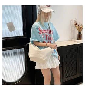 Detailed side view of off-white canvas dumpling bag with stylish pleated strap on model