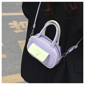 Detail einer lila-grünen Mini Boston Tasche, kombiniert mit schwarzem Blazer auf der Straße