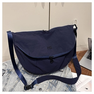 Detail of navy blue nylon messenger bag with MS embroidery and adjustable strap