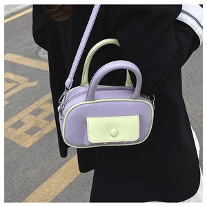 Detail der kontrastfarbenen Mini-Boston-Tasche in Lila und Grün mit Umhängeriemen und Griff