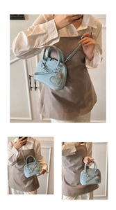 Detail view of light blue lychee leather shell bag with heart charm and silver hardware