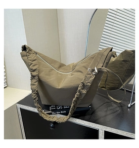 Detail of brown pleated shoulder strap and drawstring metal buckle on tote bag