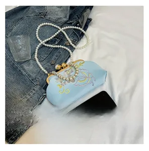 Detail of light blue satin evening bag with floral embroidery and pearl chain straps