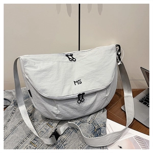Close-up of white nylon messenger bag with MS logo, dual zippers and adjustable wide strap
