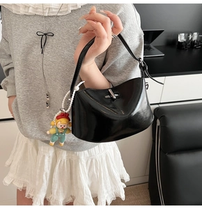 Detail of black glossy crescent shoulder bag with silver twist lock and charm