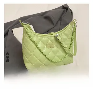 Detailed view of green quilted crescent bag with woven chain and gold twist lock closure