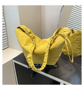 Detail of ginger yellow dumpling bag featuring unique ruched shoulder strap and nylon texture