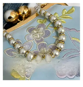 Close-up of exquisite floral embroidery and pearl handle with gold rhinestone spacers