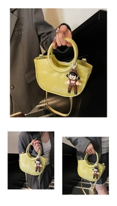 Detail of light green bucket bag with circular handle and cute doll charm accessory