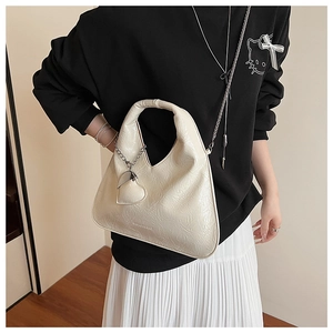 Detail of cream triangle handbag with crinkled texture and heart-shaped pendant charm